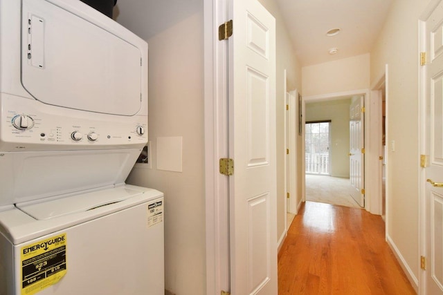 washroom with light hardwood / wood-style floors and stacked washer / dryer