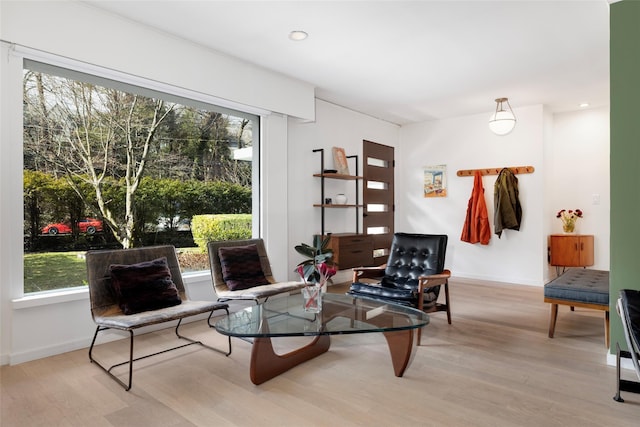 living area with a wealth of natural light, recessed lighting, baseboards, and wood finished floors