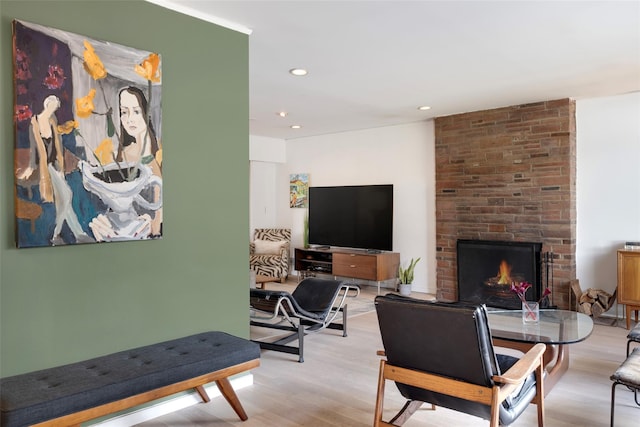 living room with recessed lighting, a brick fireplace, and light wood finished floors