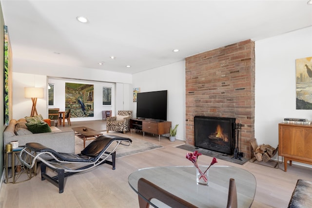 living area with a brick fireplace, recessed lighting, and light wood finished floors