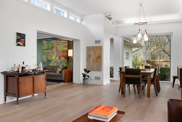 dining space with baseboards, a high ceiling, and light wood-style floors