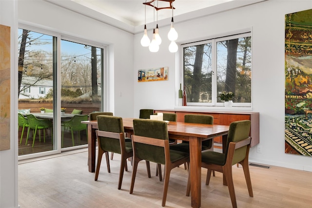 dining space featuring baseboards, visible vents, and light wood finished floors