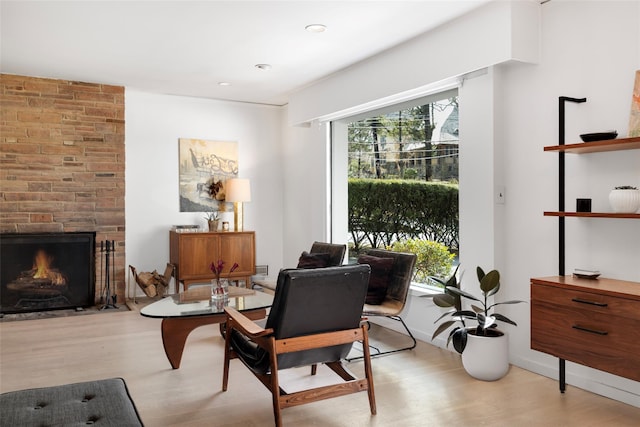 sitting room with baseboards, a healthy amount of sunlight, light wood-type flooring, and a large fireplace