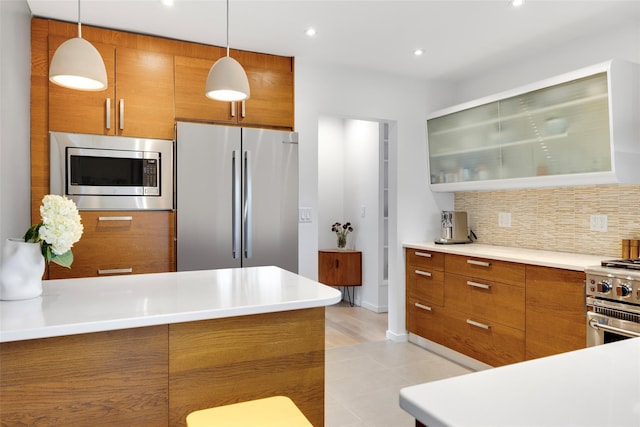 kitchen featuring hanging light fixtures, brown cabinets, backsplash, and stainless steel appliances