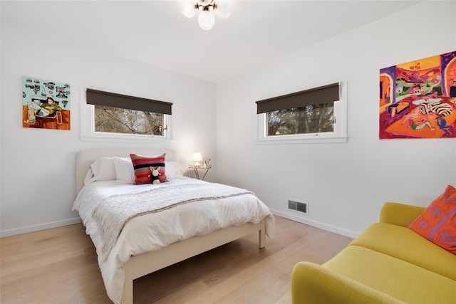 bedroom featuring visible vents, light wood-type flooring, and baseboards