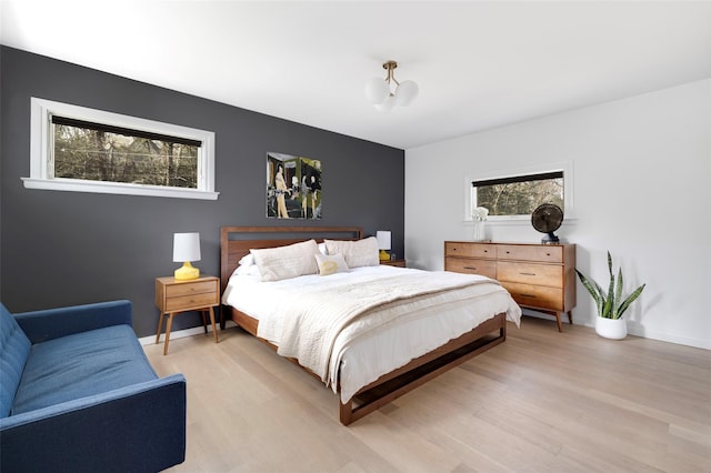 bedroom with multiple windows, baseboards, and light wood-type flooring