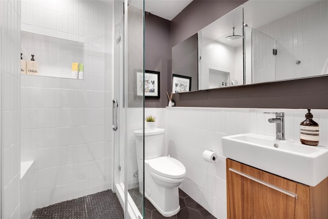 bathroom featuring vanity, a wainscoted wall, a stall shower, tile walls, and toilet