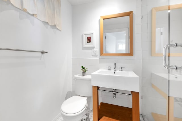 bathroom featuring a shower, toilet, tile walls, and vanity