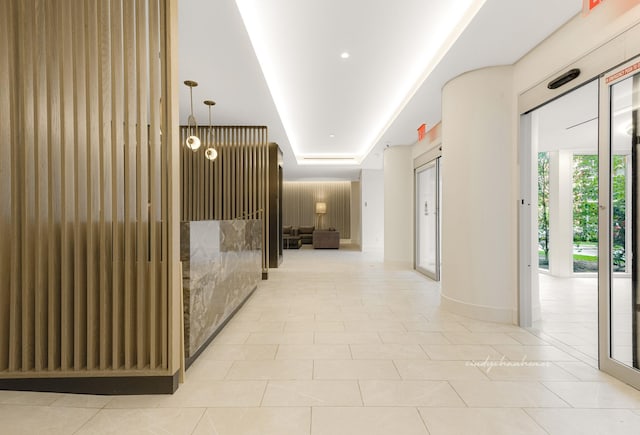 corridor featuring light tile patterned flooring and a tray ceiling