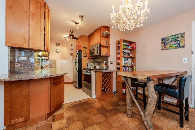 kitchen with sink, hanging light fixtures, stainless steel appliances, light stone countertops, and decorative backsplash