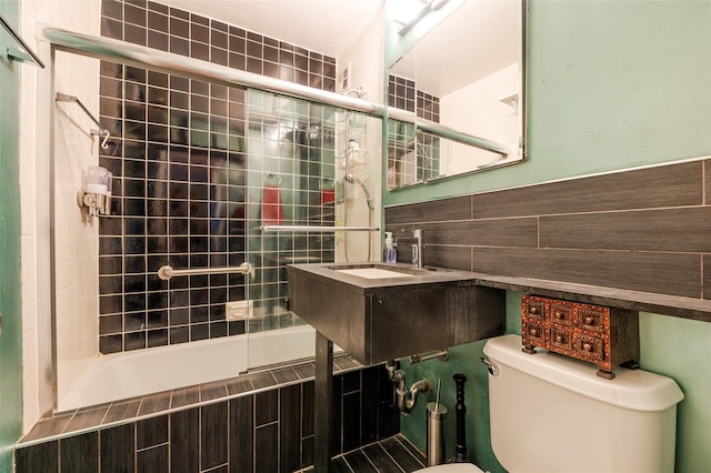 full bathroom with enclosed tub / shower combo, toilet, sink, and tile walls