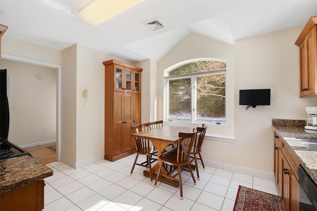 tiled dining space featuring vaulted ceiling