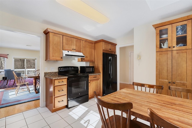 kitchen with black appliances, dark stone counters, and light tile patterned flooring