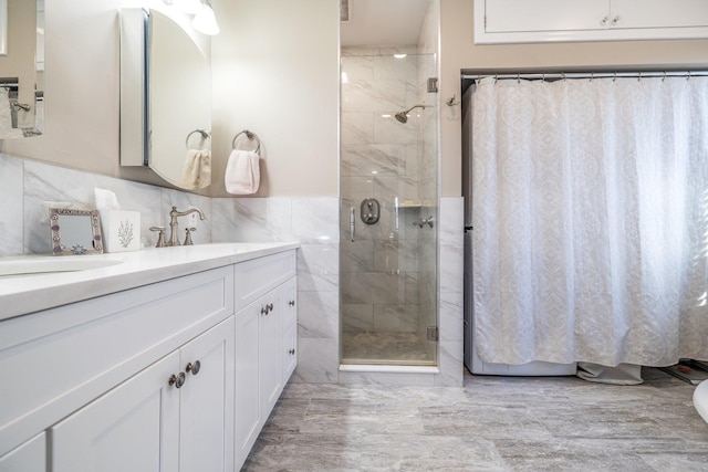 bathroom with a shower with door, vanity, and tile walls