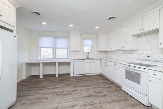 kitchen with white cabinetry, white appliances, and sink