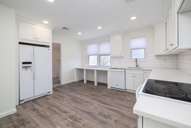 kitchen featuring sink, white cabinetry, hardwood / wood-style flooring, white appliances, and backsplash