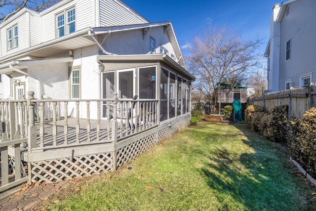 exterior space featuring a playground, a wooden deck, a sunroom, and a yard