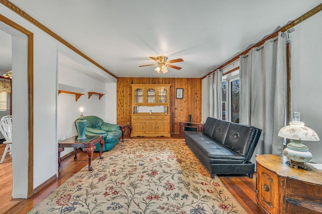 living room with hardwood / wood-style floors, ceiling fan, and wood walls