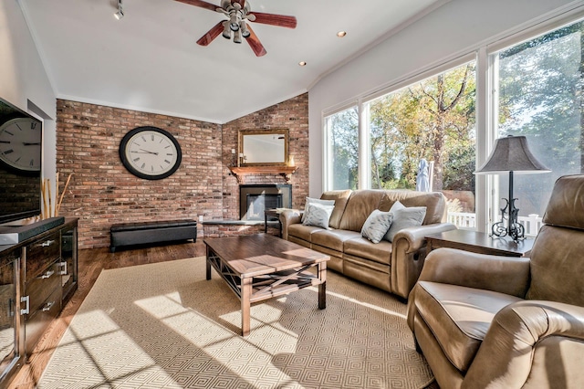 living room with vaulted ceiling, brick wall, a fireplace, ceiling fan, and light hardwood / wood-style floors