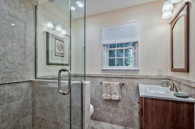 bathroom with vanity, toilet, a shower with door, and tile walls