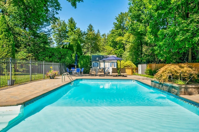 view of swimming pool featuring a patio, pool water feature, and a storage shed