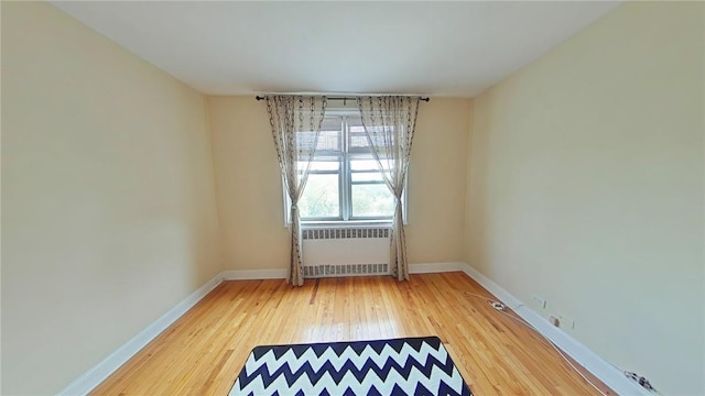 unfurnished room with radiator and hardwood / wood-style floors