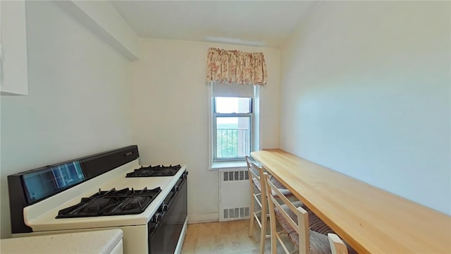 kitchen with white range with gas cooktop, radiator heating unit, and light wood-type flooring