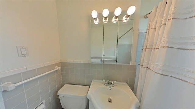 bathroom with a shower with shower curtain, toilet, sink, and tile walls