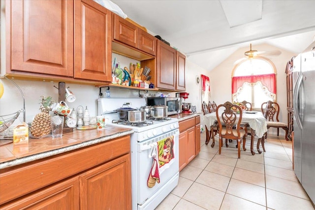 kitchen featuring lofted ceiling, light tile patterned floors, and stainless steel appliances