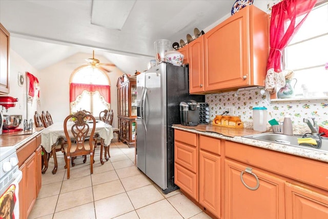 kitchen with stainless steel refrigerator with ice dispenser, lofted ceiling, sink, light tile patterned floors, and stove