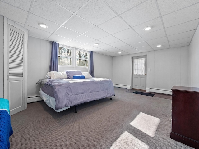 carpeted bedroom with baseboard heating and a drop ceiling