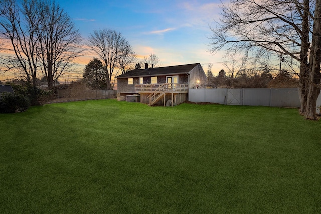 back house at dusk featuring a yard and a deck