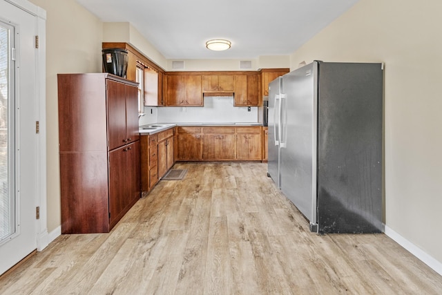 kitchen featuring sink, stainless steel refrigerator, and light hardwood / wood-style flooring