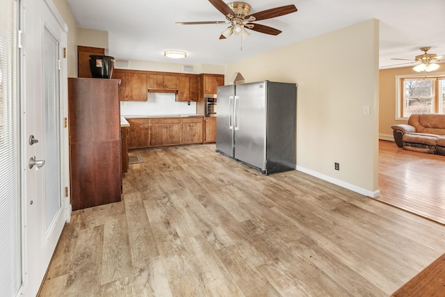 kitchen featuring stainless steel fridge, ceiling fan, and light wood-type flooring