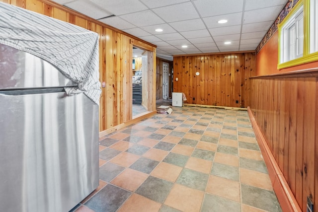 basement with a drop ceiling and wood walls