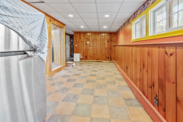 hallway featuring wooden walls and a paneled ceiling