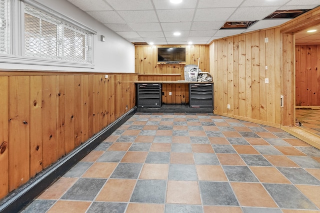 bar featuring beverage cooler, a drop ceiling, and wood walls