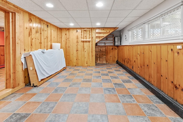 interior space featuring a drop ceiling and wood walls