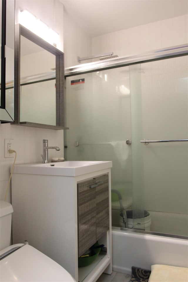 full bathroom with toilet, vanity, and bath / shower combo with glass door