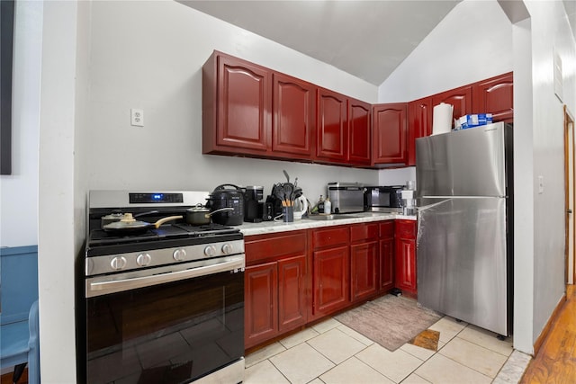 kitchen with stainless steel appliances, vaulted ceiling, and light tile patterned floors