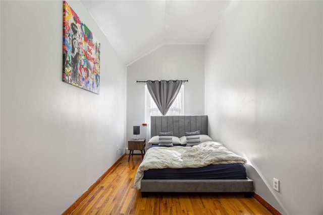 bedroom with vaulted ceiling and hardwood / wood-style floors