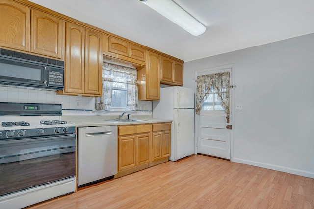 kitchen with sink, gas stove, stainless steel dishwasher, white fridge, and light hardwood / wood-style floors