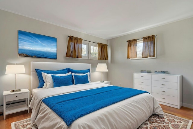 bedroom with a baseboard radiator and light wood-type flooring