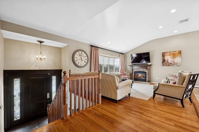 living room featuring hardwood / wood-style flooring, lofted ceiling, and a chandelier