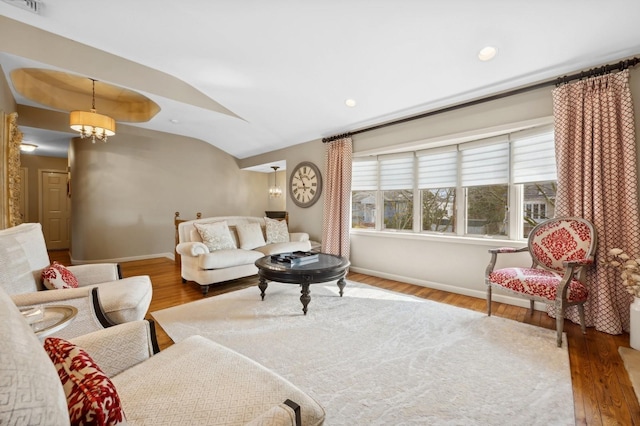 living room with lofted ceiling, hardwood / wood-style floors, and an inviting chandelier