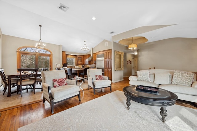 living room with lofted ceiling, wood-type flooring, and a chandelier