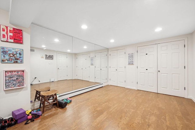 exercise area featuring hardwood / wood-style floors and a baseboard radiator