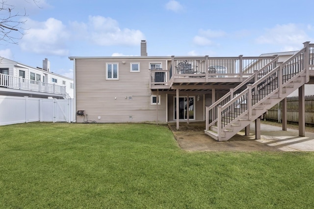 rear view of house with a wooden deck, a patio area, and a lawn