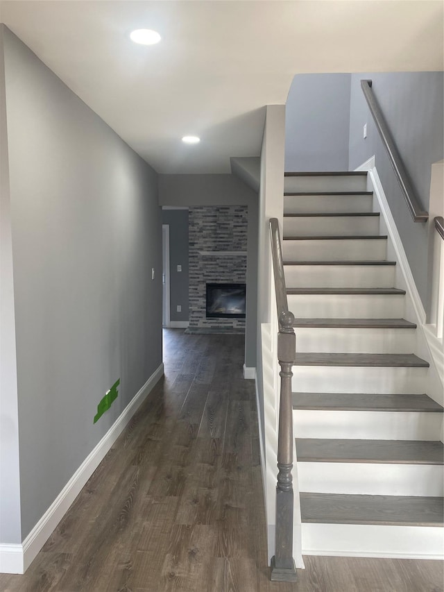 staircase with hardwood / wood-style flooring and a large fireplace