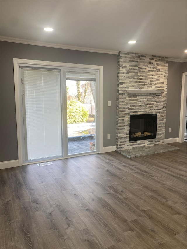 unfurnished living room featuring crown molding, dark wood-type flooring, and a stone fireplace